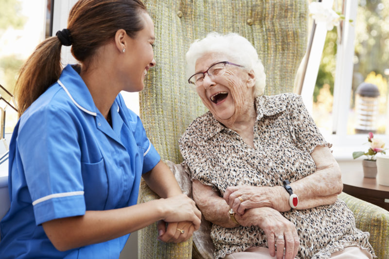 Une aide-soignante qui rigole avec une personne âgée