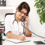 Young woman doctor talking by phone